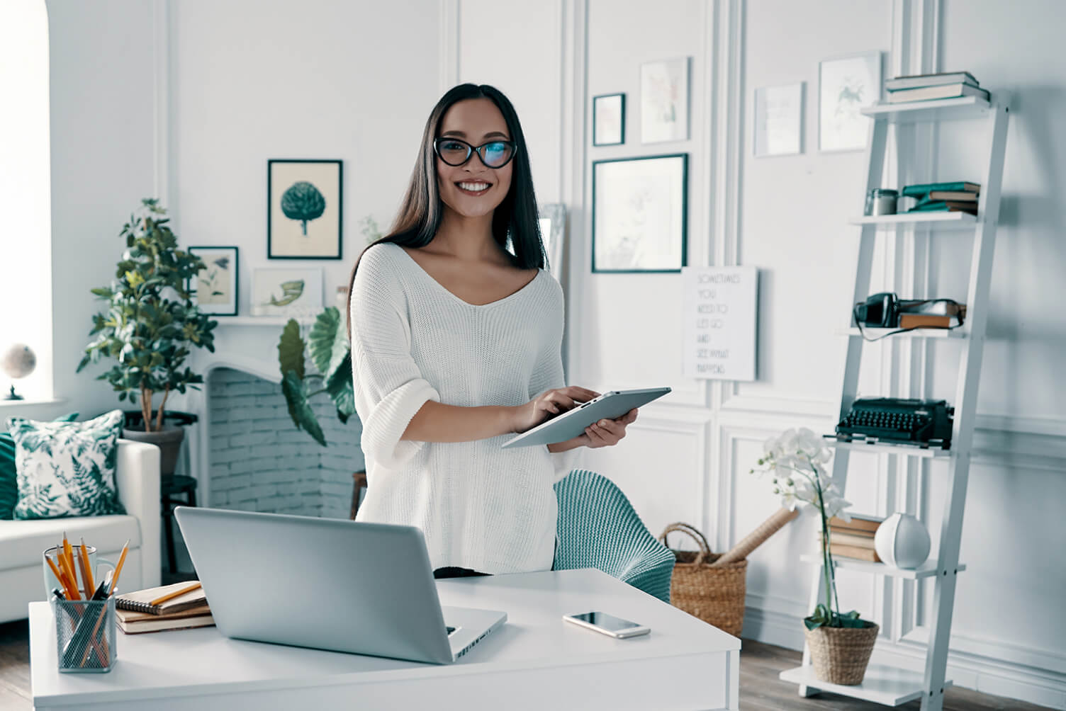 Mujer sonriendo con computador y tablet.